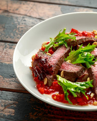 Beef Steak with Romesco sauce, nuts and vegetables on white plate