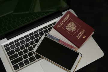 Laptop and smartphone and Visa stamp, American Visa, travel passport and Russian passport. Business and vacation and travel concept. Flat lay. Top view.
