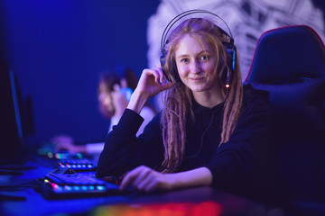 Call center beautiful girl operator professional gamer smiling and talking into a microphone, dark blue neon background
