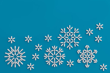 A lot of pills scattered on a blue background in the form of snowflakes . 3D illustration