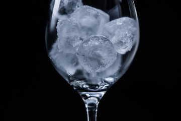 Studio shot of glass with ice cubes against black background.