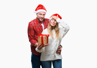 Young couple in love wearing christmas hat and holding present over isolated background stressed with hand on head, shocked with shame and surprise face, angry and frustrated. Fear 