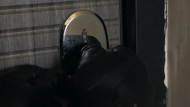 Hands in gloves opening the lock with picklocks