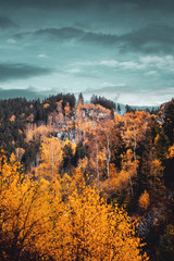 Colorful autumn fall trees with mountain rocks and dramatic clouds. Okertalsperre, Harz National Park in Germany