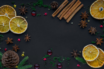 Fototapeta na wymiar Merry Christmas and happy new year. composition on a black background of Christmas tree branches, cones, toys, cinnamon, dried oranges and anise. Greeting background, card or layout design. copy space