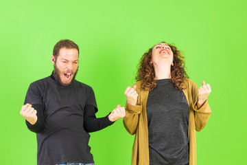 Beautiful young couple over green background celebrating surprised and amazed for success with arms raised. Winner concept.