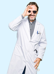 Handsome middle age doctor man wearing sunglasses doing ok gesture with hand smiling, eye looking through fingers with happy face.