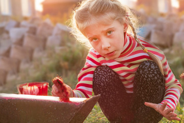 sunset. Blond girl paints a metal ladder with a brush. color is red. there is a shutter. soft...