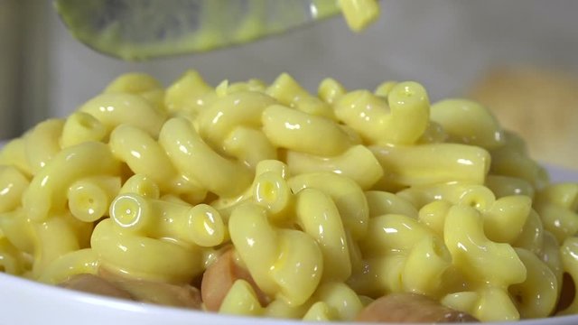 Spooning macaroni and cheese into a bowl closeup, slow motion