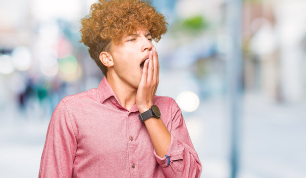 Young handsome business man with afro hair bored yawning tired covering mouth with hand. Restless and sleepiness.