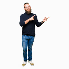 Young blond man wearing glasses and turtleneck sweater smiling and looking at the camera pointing with two hands and fingers to the side.