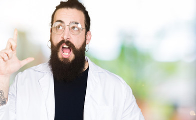 Fototapeta premium Doctor therapist man with long hair and bear wearing white coat pointing finger up with successful idea. Exited and happy. Number one.