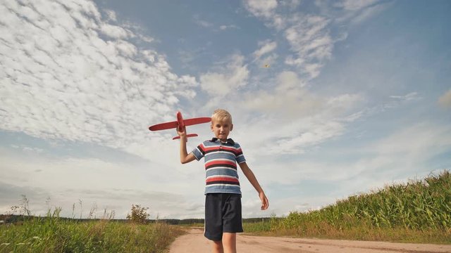 A little boy runs and launches a paralon toy airplane.
