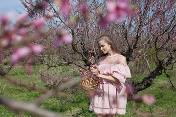 Beautiful blonde woman in dress collects flowers in the garden