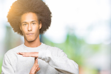 Young african american man with afro hair wearing sporty sweatshirt Doing time out gesture with...