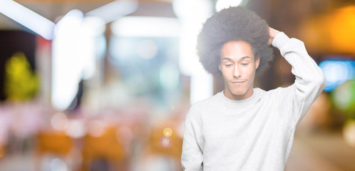 Young african american man with afro hair wearing sporty sweatshirt confuse and wonder about...