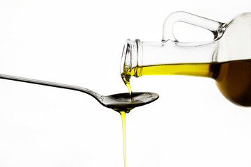 pouring olive oil from glass bottle on white background