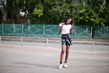 African american dark skinned slim model posed in a black leather shorts and white t-shirt.