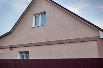 Facade of country house with steel fence and windows on the sky background