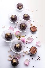 Top view vertical shot handmade chocolates with nuts and honey on a white background with rose petals.