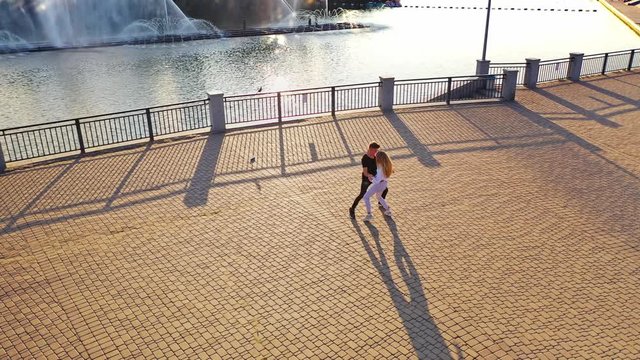 Modern dancers are dancing in the street. Urban lifestyle. Hip-hop generation. Boy's and girl's emotional moves on the video. Paving stones and young dacing couple at fontain background. Aerial view. 