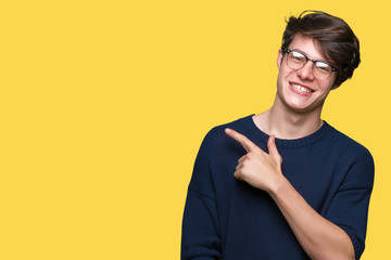 Young handsome man wearing glasses over isolated background cheerful with a smile of face pointing with hand and finger up to the side with happy and natural expression on face