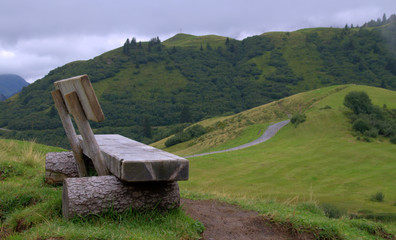 Wooden bench in the Alps and a hike road