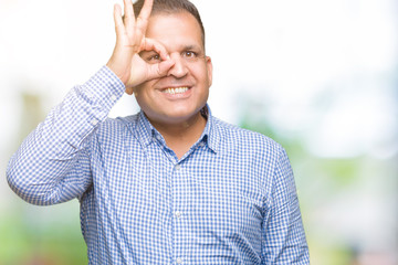 Middle age arab business man over isolated background doing ok gesture with hand smiling, eye looking through fingers with happy face.