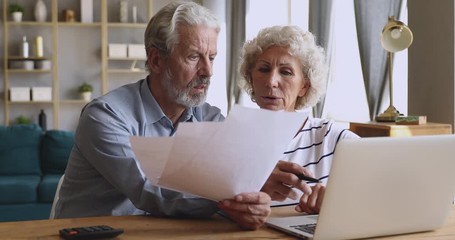 Worried senior couple checking calculating bills discuss unpaid debt taxes - Powered by Adobe