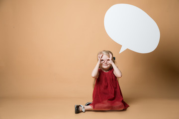 Girl sit on the floor on an orange background. Girl is very happy. Of the girl hanging blank white speech