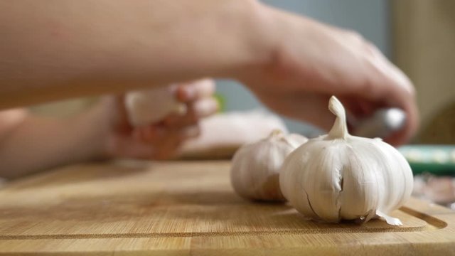 closeup head of garlic, male hands peel the garlic on a wooden board