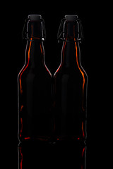 two glass beer bottles on a black background