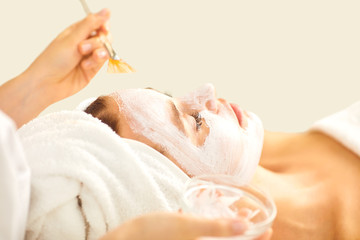 A cosmetologist applies a mask to a woman.