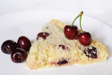 A slice of sweet homemade cherry pie on a white plate with ripe cherries on the top