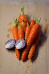 Fresh wet organic carrots two halves of red onion on a cutting board
