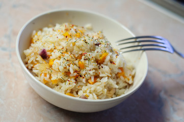 Hot steaming rice with vegetables under spices in a bowl with a fork