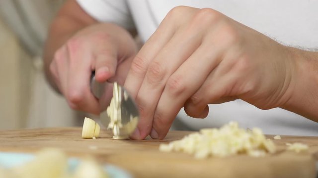 male hands cut garlic on a wooden board. close-up