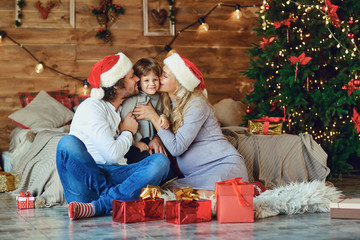 Family kisses the child in the house at Christmas.