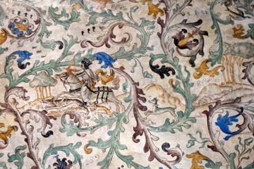Fragment of the ancient castle wall. There is a fresco on the wall. The painting shows hunting.
