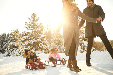 Happy family sledding in the park in winter.