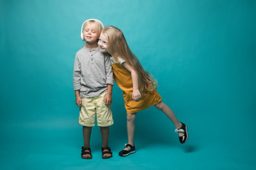 Very emotional children listen to music with headphones on a blue background. Boy and girl are dancing and showing different emotions and he is happy