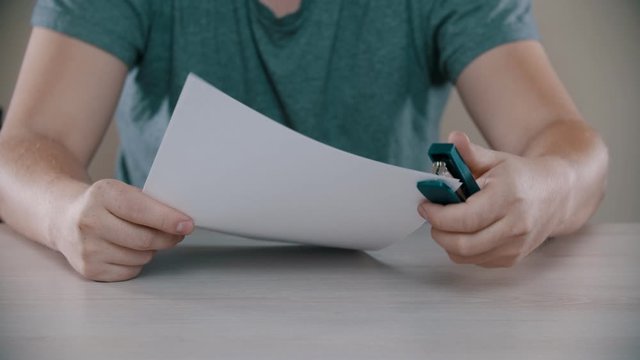 A man is nervously fastening a paper by stapler