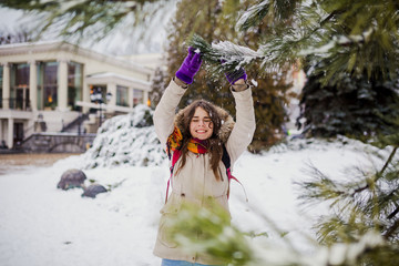 Obraz na płótnie Canvas Beautiful young Caucasian woman joy happiness smile play with snow near a coniferous tree in a snowy park