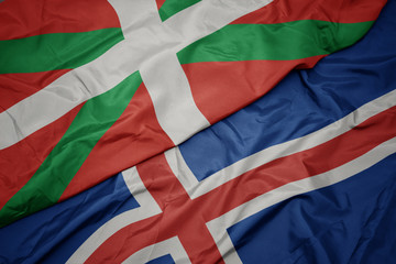 waving colorful flag of iceland and national flag of basque country.