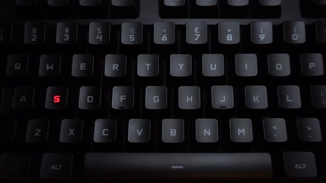 The word sos is typed on a luminous computer keyboard. Black backlit keyboard with letters. The keyboard itself prints the word using the backlight.