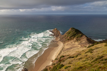 Cape Reinga, Te Rerenga Wairua, the northernmost point of New Zealand where the Tasman Sea and Pacific Ocean meet, in evening sun with some clouds.