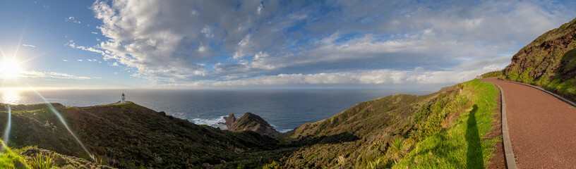 Cape Reinga, Te Rerenga Wairua, the northernmost point of New Zealand where the Tasman Sea and Pacific Ocean meet, in evening sun with some clouds.