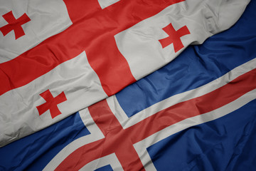 Fototapeta premium waving colorful flag of iceland and national flag of georgia.