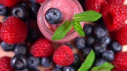 Top view of fresh blended fruit smoothierotating among forest berries, 4K video shot 2in1. Protein ingredients for human health. Fresh colorful forest berries and full vitamin complex - Powered by Adobe