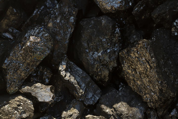 Black coal mine close-up with soft focus. Anthracite coal bar on dark background. Natural black coal bars for background. Industrial coal nuggets close up